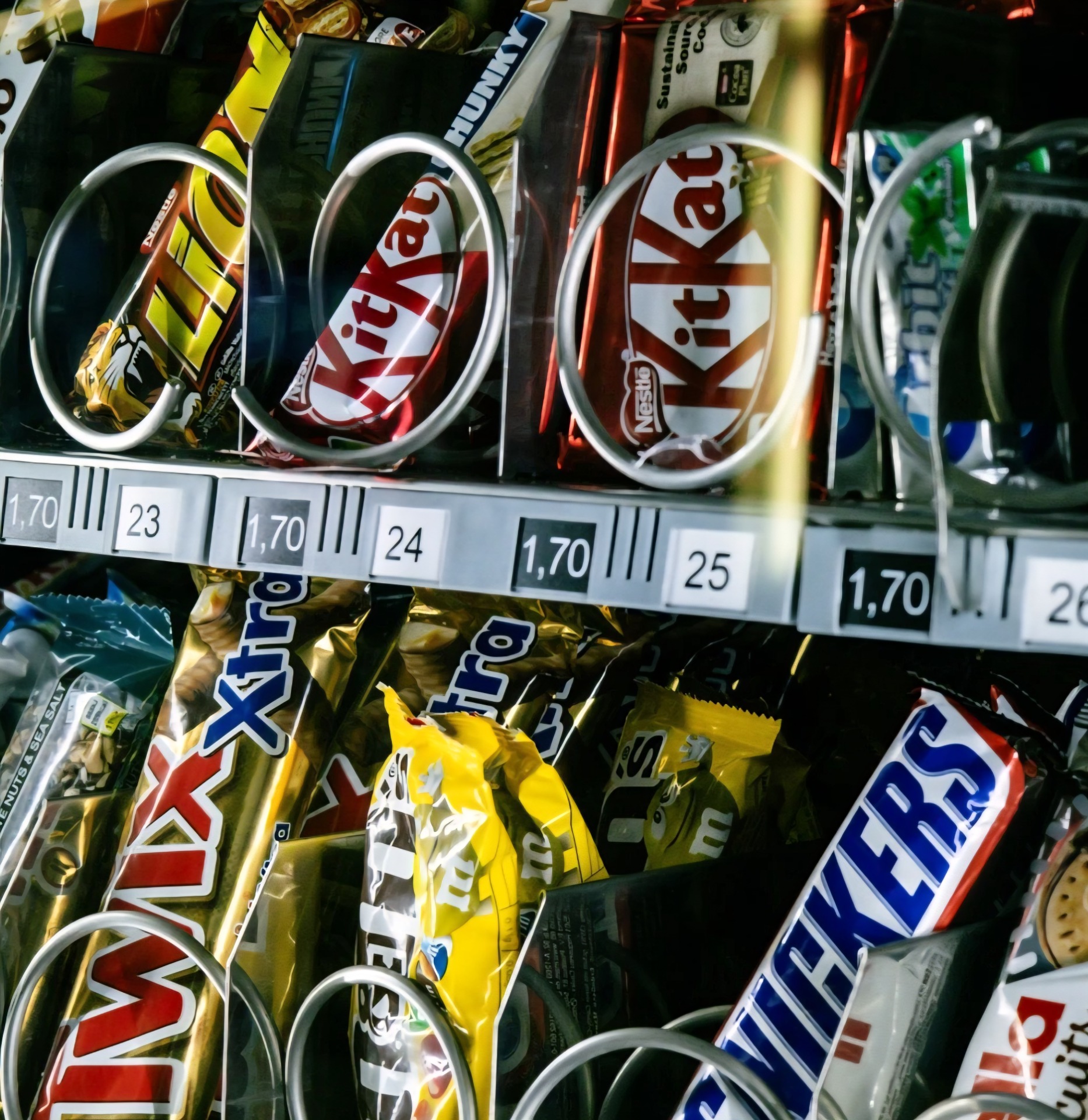 Close up of a vending machine filled with an assortment of candy bars and other tasty snacks.